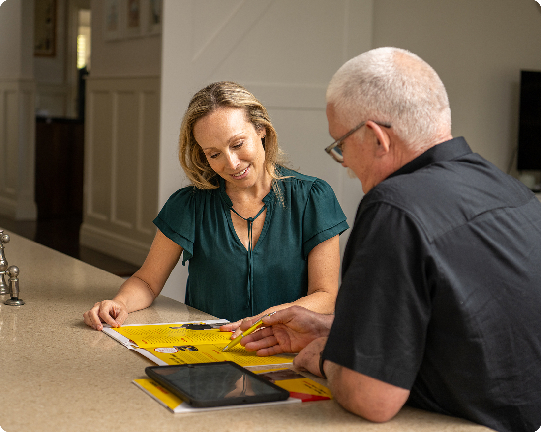 Couple reviewing documents and tablet at kitchen counter.