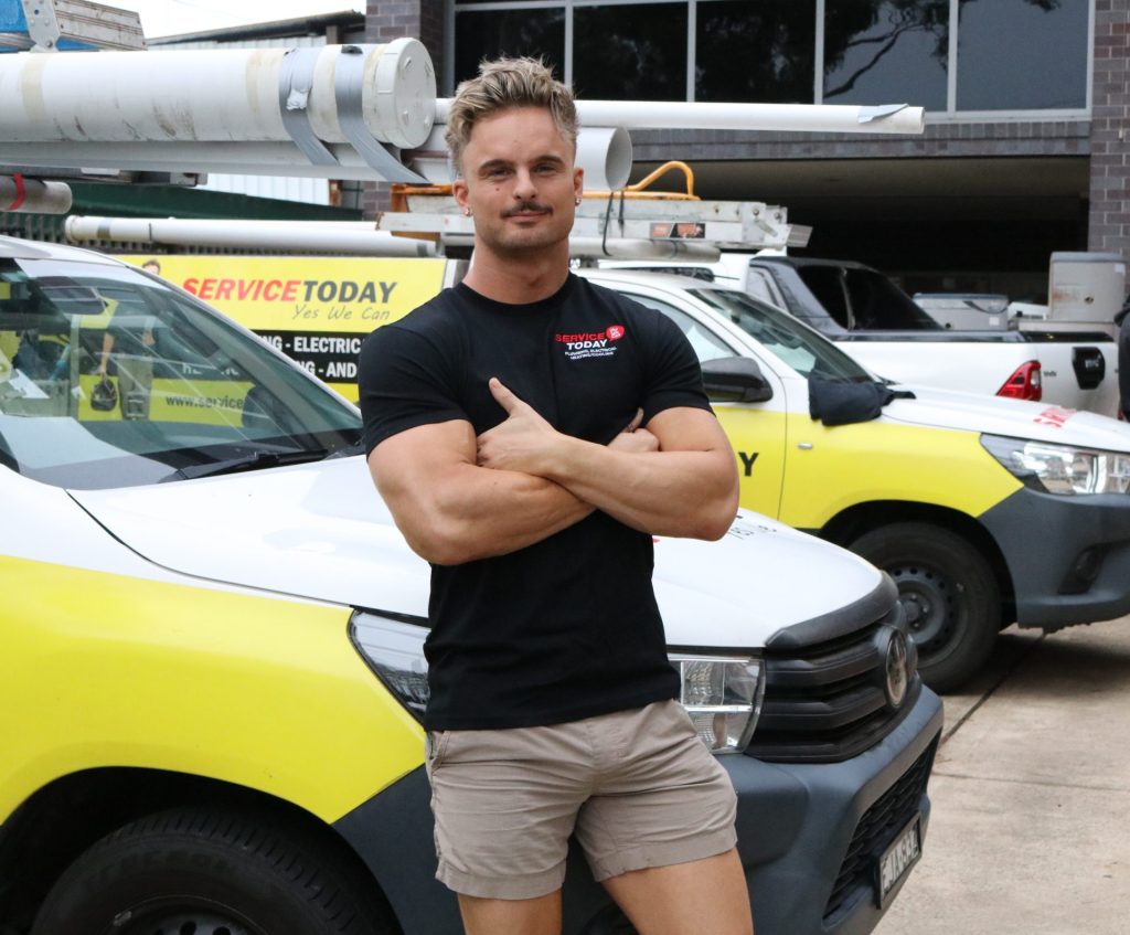 Joey from Service Today, a plumbing and electrical company, with his company vehicles.