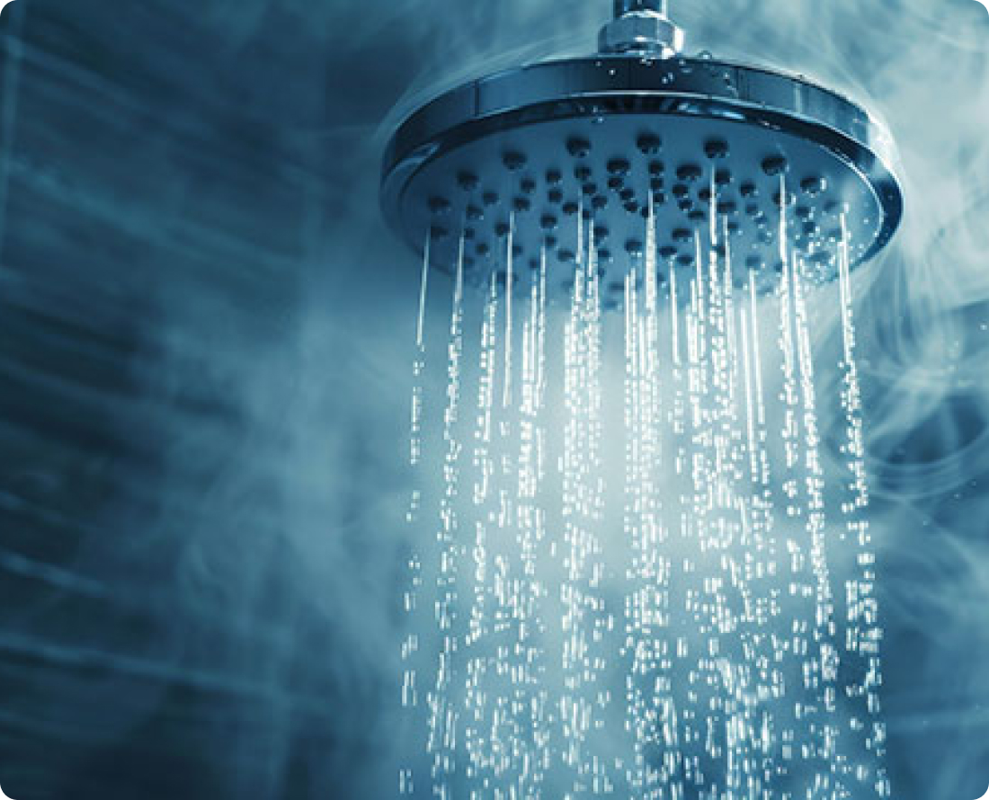 Close-up of a chrome shower head with steaming hot water cascading down, suggesting a relaxing or invigorating shower experience.