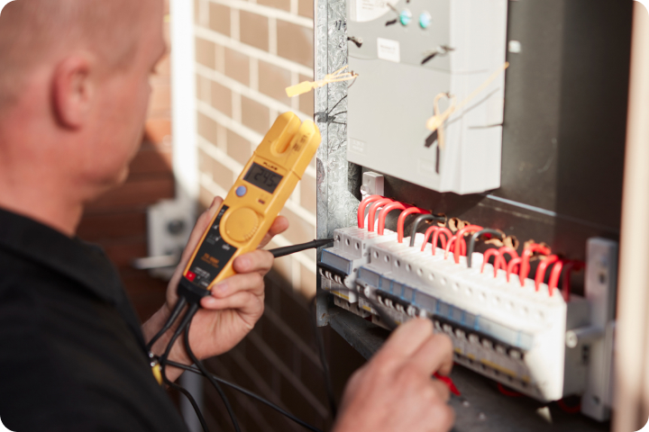 Electrician testing wiring with a multimeter in a garage.