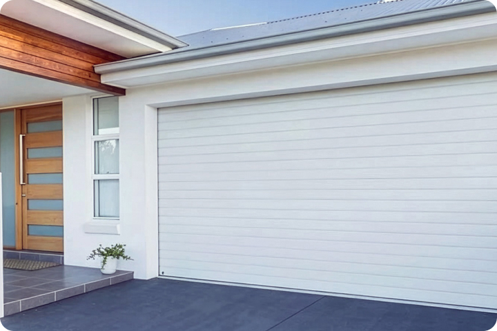 Modern white horizontal garage door next to a wooden front door.