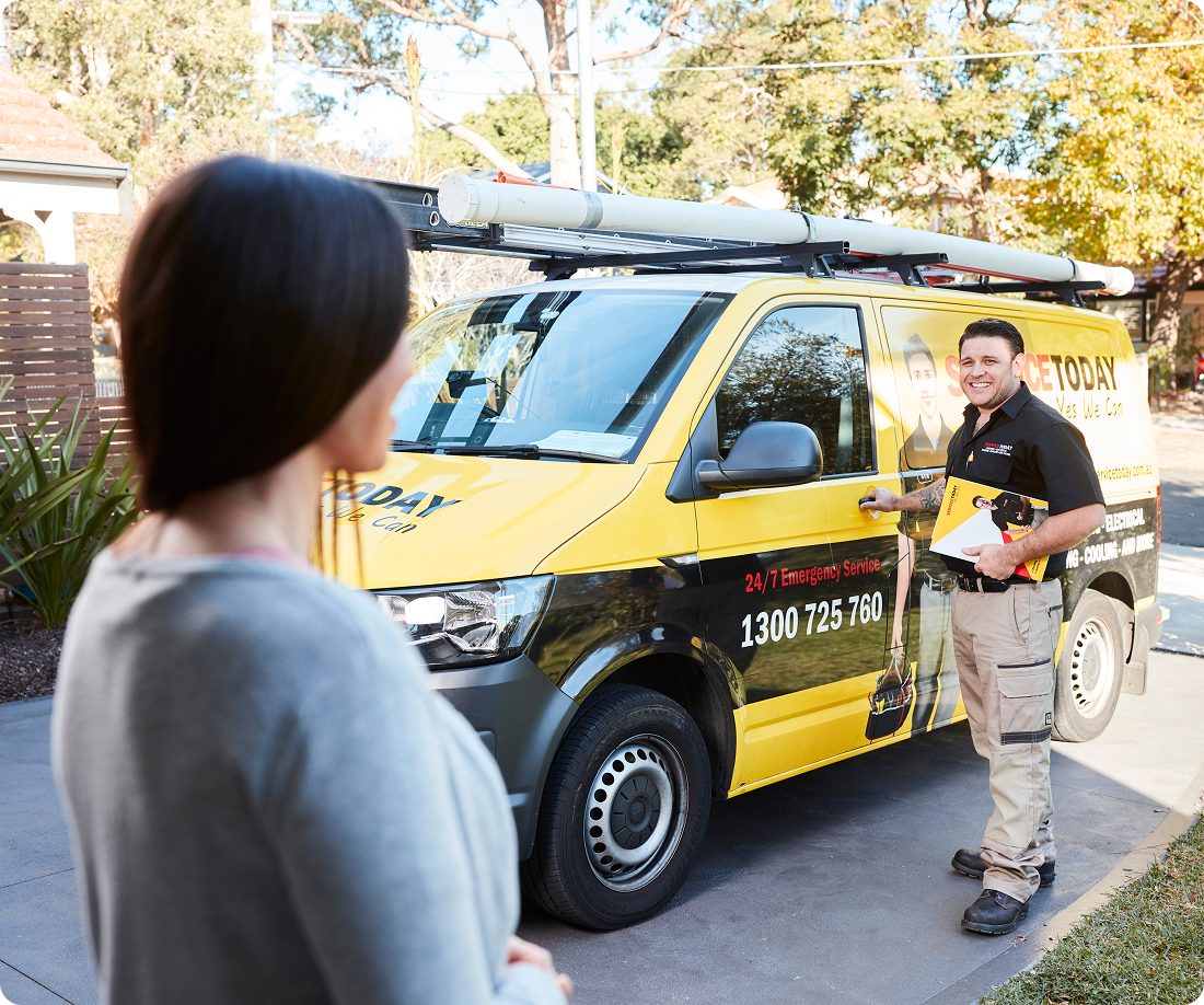 A man in a uniform stands by a yellow service van holding a brochure.