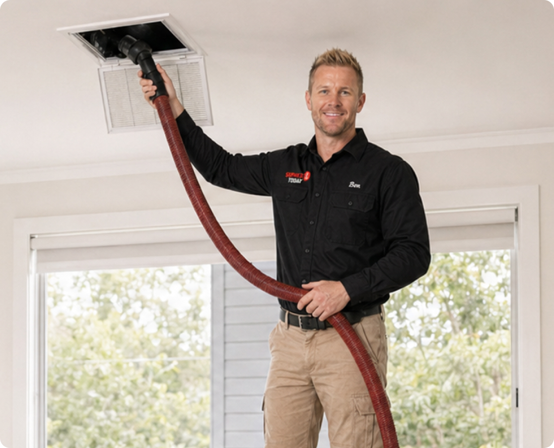 Man cleaning air vent with a hose, providing duct cleaning services for a home.