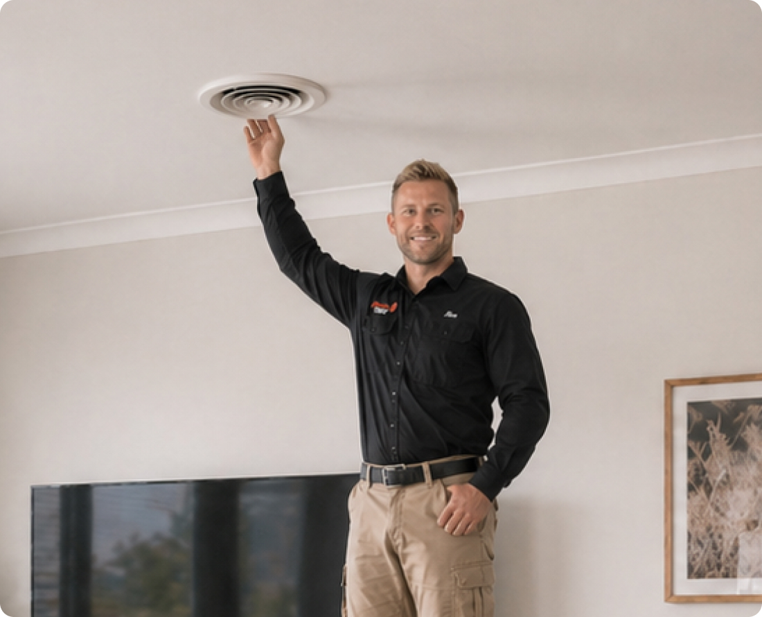 HVAC technician inspecting ceiling air vent for duct cleaning service.