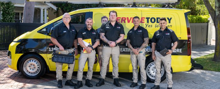 Service Today team of tradesmen, in uniform, standing in front of their branded yellow van.